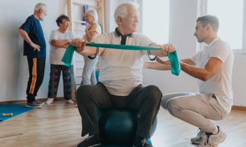 Older man exercising on a ball on a group classes with instructor